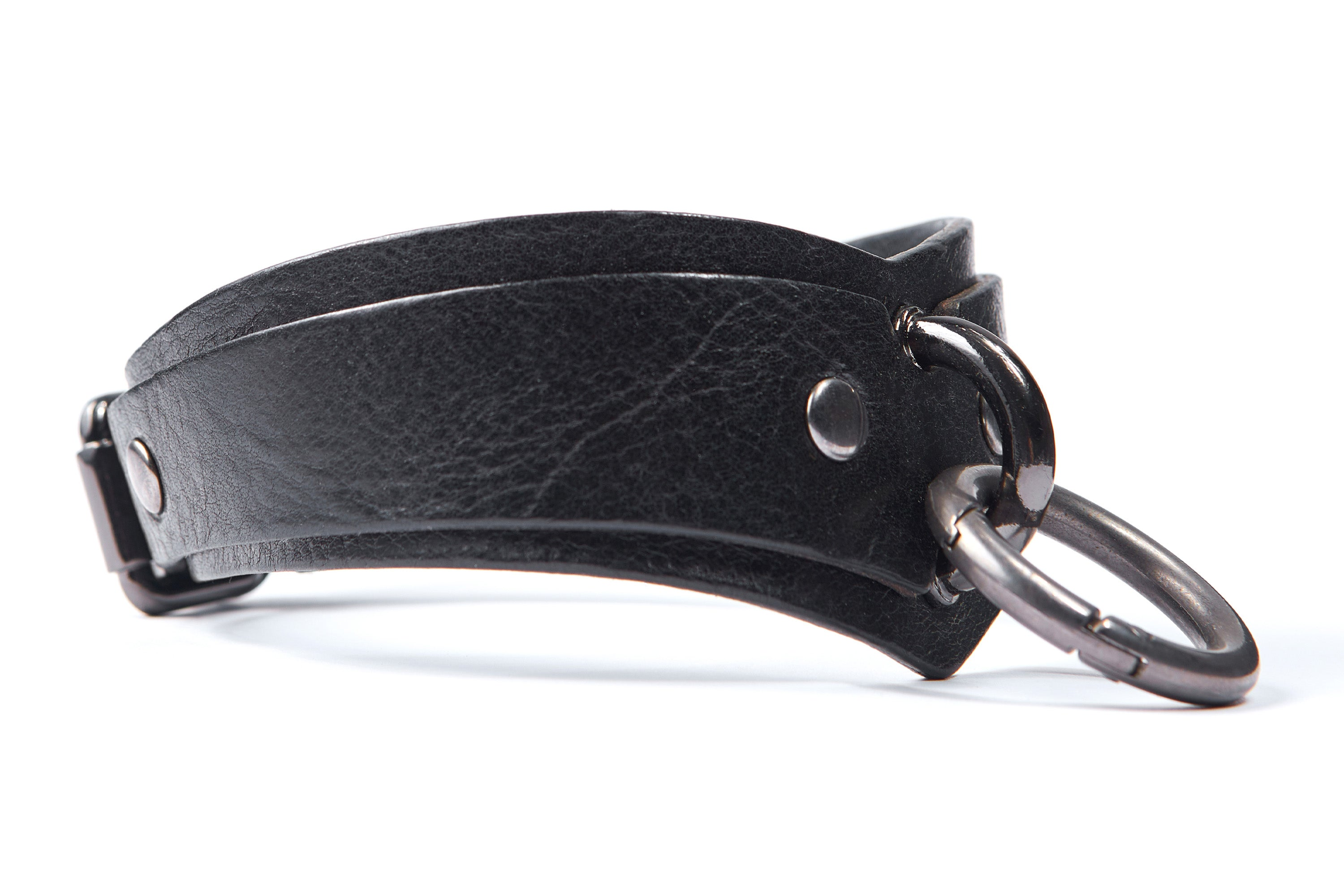 Black arc-shaped BDSM collar with D-ring and O-carabiner for attaching a leash, handcuffs or other bondage accessories. Dark nickel hardware. Side view. Black arc-shaped BDSM collar with D-ring and O-carabiner for attaching a leash, handcuffs or other bondage accessories. Dark nickel hardware. Side view.