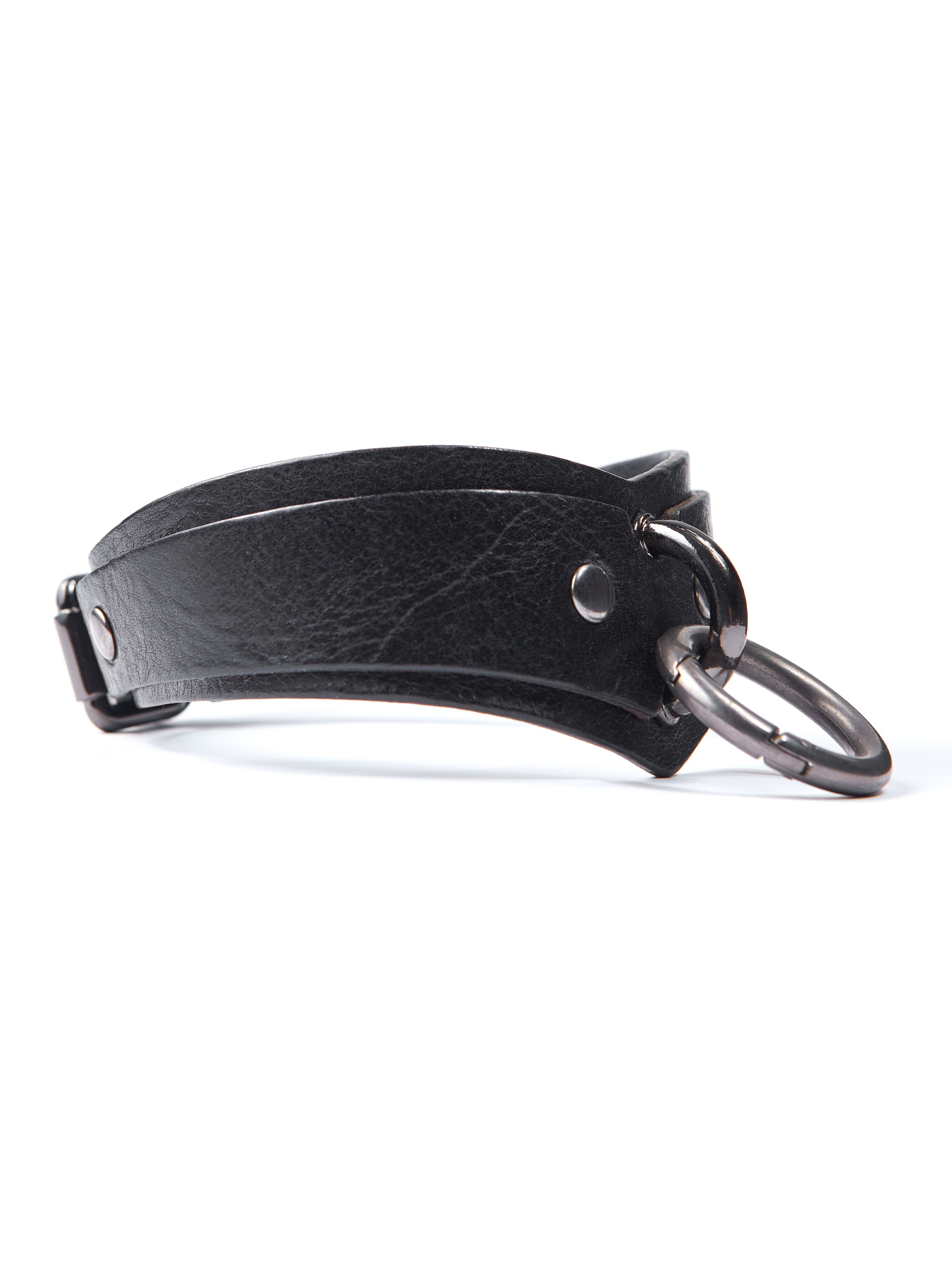 The photo shows the bondage collar close-up, side view. Shown are D-rings for securing handcuffs, leash and other accessories, made of black leather 2.4-3 mm thick and dark nickel hardware.