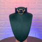 Mannequin head with a blue leather collar featuring a gold ring on a textured purple background