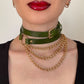 Green leather choker and gold chain necklace on a neutral background