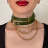 Green leather choker and gold chain necklace on a neutral background