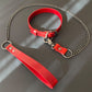 Red leather collar with chain leash on a gray surface