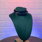 Green leather choker on a mannequin bust against a textured purple wall.