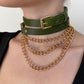 Green leather choker and gold chain necklace on a person against a neutral background