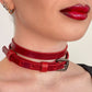 Close-up of a person wearing a red leather choker with a neutral background