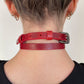 Red leather choker worn by a person on a plain background