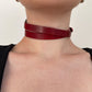 Red leather choker worn by a person on a neutral background