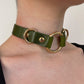 Green leather choker with gold rings on a person's neck against a neutral background