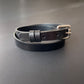Black leather choker with a silver buckle on a gray background