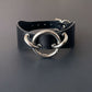 Black leather collar with silver metal rings on a gray background