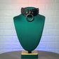 Black leather choker with a large ring on a green mannequin bust against a textured white wall.