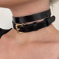 Black leather choker with a gold buckle on a person's neck.