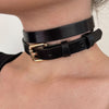 Black leather choker with a gold buckle on a person's neck.
