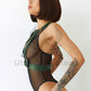 Wide chest straps with D-rings for attaching handcuffs or other accessories. Side view of the model. The harness is worn backwards and is versatile. Gold hardware, green leather.