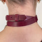 Burgundy leather choker worn by a person on a neutral background