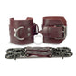 Marsala leather handcuffs with two connectors with carabiners are lying side by side, one handcuff is shown with a buckle and it stands on a rib, the second handcuff is shown with a D-ring for which the carabiners are attached and it also stands on a rib. Front view. Dark nickel hardware. 