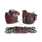 Marsala leather handcuffs with two connectors and carabiners lie side by side, one handcuff is shown from the side of the buckle and lies half sideways the second handcuff stands half sideways and is shown from the side of the D-ring for which the carabiner is fixed. Dark nickel hardware. 