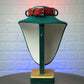 Green lamp with a red collar on a textured white background