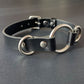 Black leather collar with silver hardware on a gray background