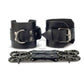 Black leather handcuffs with two connectors with carabiners are lying side by side, one handcuff is shown with a buckle and it stands on a rib, the second handcuff is shown with a D-ring for which the carabiners are attached and it also stands on a rib. Front view. Dark nickel hardware. 