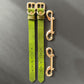 Two green leather cuffs straps with gold buckles on a gray background