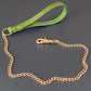 Green leather bondage leash with gold chain on a dark gray background