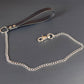 Bondage leash with leather handle and metal chain on a gray background