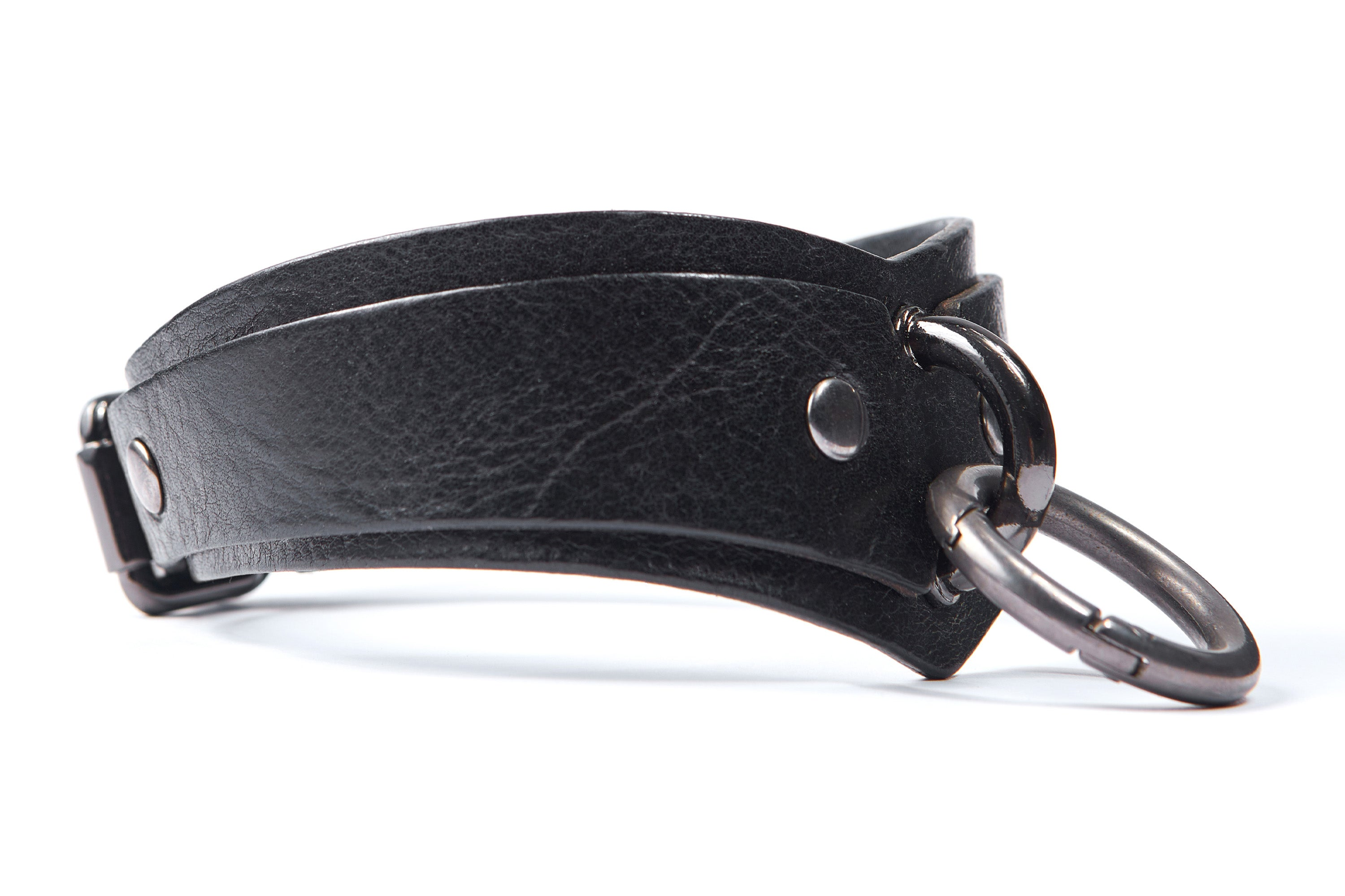 Black arc-shaped BDSM collar with D-ring and O-carabiner for attaching a leash, handcuffs or other bondage accessories. Dark nickel hardware. Side view.