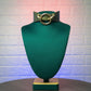 Green mannequin head with a green collar and gold hardware on a textured white background