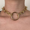 Gold chain necklace worn around the neck on a neutral background