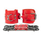 Red leather handcuffs with two connectors with carabiners are lying side by side, one handcuff is shown with a buckle and it stands on a rib, the second handcuff is shown with a D-ring for which the carabiners are attached and it also stands on a rib. Front view. Dark nickel hardware. 