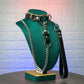 Leather collar with chain and strap on a green mannequin head against a textured wall.