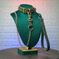 Green leather collar with gold chain leash and leash on a green mannequin bust against a textured white wall.