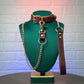 Leather collar with chain leash on a green mannequin against a textured wall background
