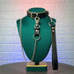 Black leather collar with chain leash on a green mannequin bust against a textured wall.