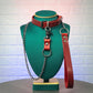 Red leather collar with chain leash on a green mannequin bust against a textured white wall.