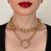 Gold chain necklace worn by a person with red lipstick on a neutral background
