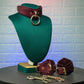Leather collar and cuffs on a green mannequin bust with a textured white brick wall background.