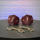 Two leather handcuffs with gold hardware on a dark surface against a textured light blue background.