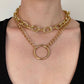 Gold chain necklace with a large ring pendant on a person wearing a black top.