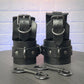Black leather handcuff and ankle cuffs with silver hardware on a gray surface.