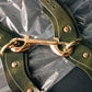 Green leather strap with gold hardware on a clear plastic background