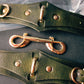 Green leather handcuffs with gold hardware on a dark surface