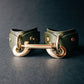 Green leather cuffs with gold hardware on a dark background