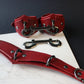 Red leather collar and cuffs set on a dark surface