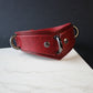Red leather collar with metal rings on a white surface and dark background