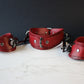 Red leather collar and cuffs on a dark background