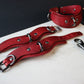 Red leather collar and cuffs with metal hardware on a white surface.