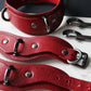 Red leather collars and cuffs on a white surface with a dark background