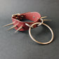 Marsala leather collar with spikes and a metal ring on a gray background
